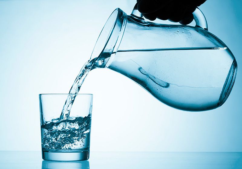 Starší žena pije doma vodu